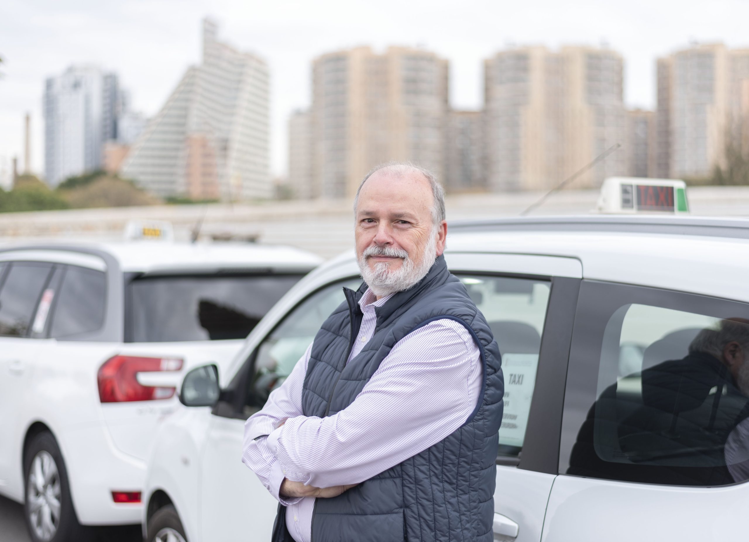 the elderly taxi driver in front of his white cab waiting for the customer